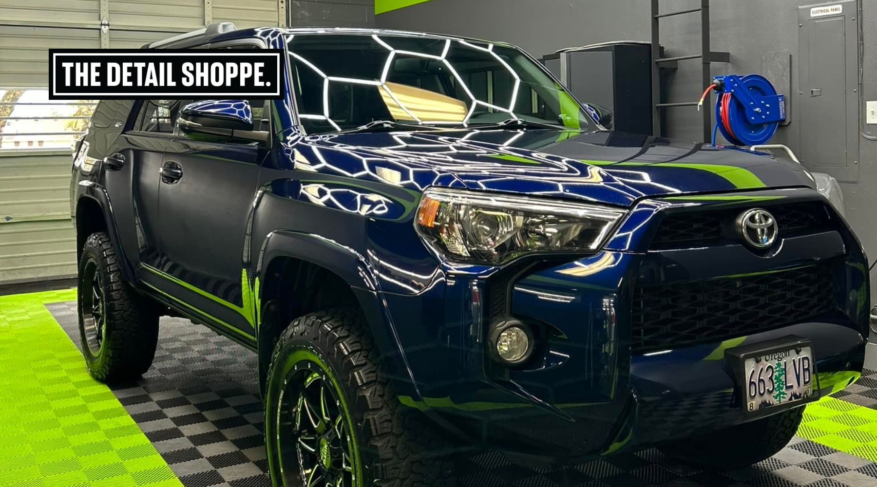 A freshly detailed dark blue Toyota SUV with glossy, protected paint reflecting overhead lights, parked inside The Detail Shoppe in Happy Valley, Oregon. The vehicle’s flawless finish highlights the benefits of professional paint protection film (PPF) maintenance.