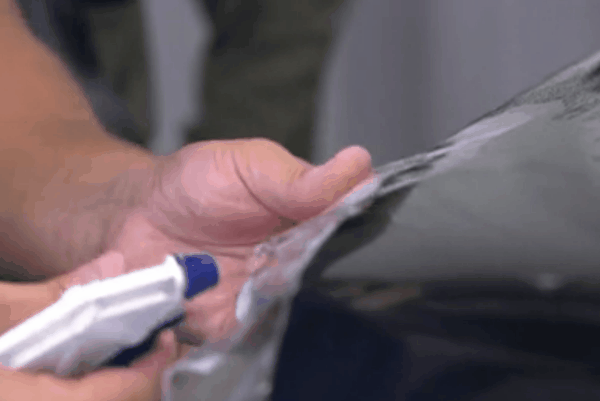 Close-up of a technician precisely trimming paint protection film during vehicle application.