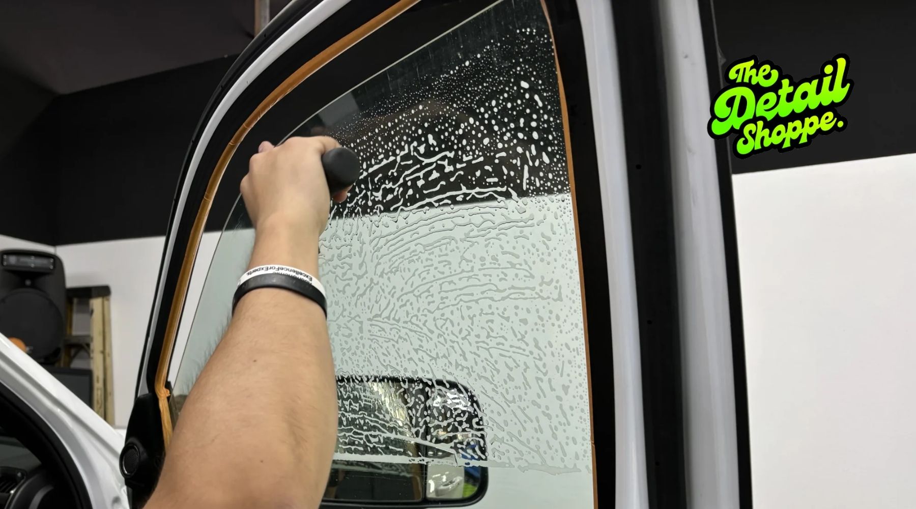 Technician applying window tint film to a vehicle window at The Detail Shoppe in Happy Valley, Oregon.