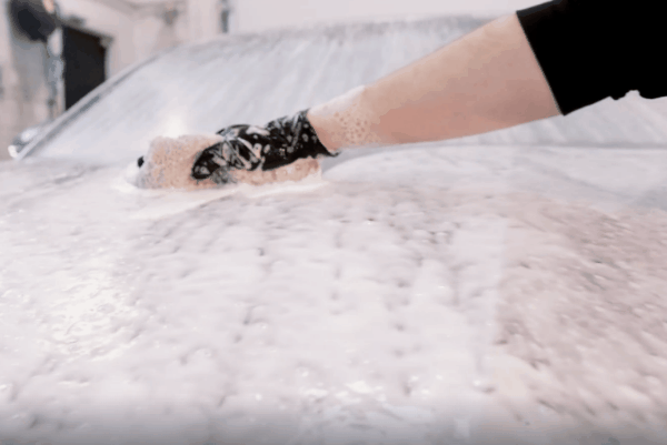 Hand washing a car covered in foam during exterior car detailing service in Happy Valley, OR