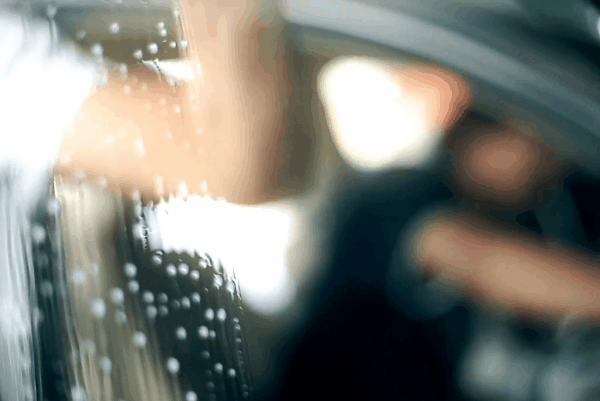 Close-up of window tint film being applied to a car window during installation