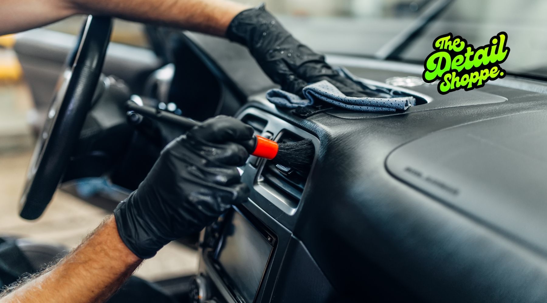 The Detail Shoppe technician cleaning dashboard vents and wiping interior surfaces during professional interior car detailing