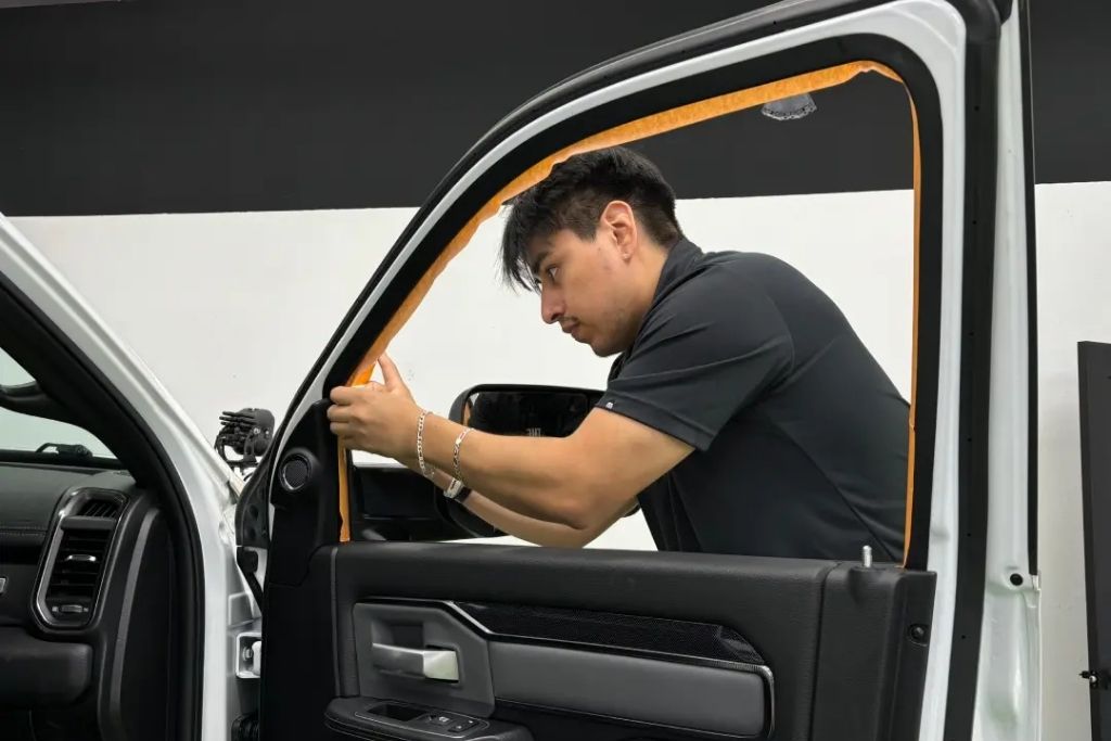 The Detail Shoppe technician applying protective masking tape around a truck door before detailing or paint correction