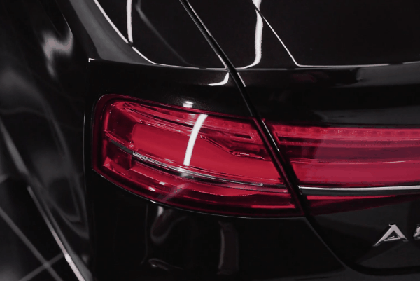 Close-up of a polished black Audi taillight showcasing a clean, glossy exterior finish after detailing