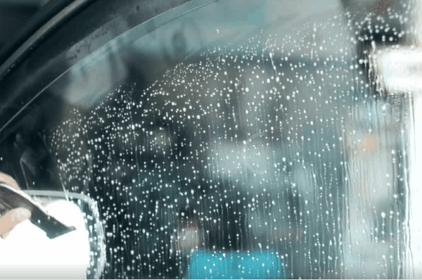 Car window being sprayed with solution during window tint installation preparation